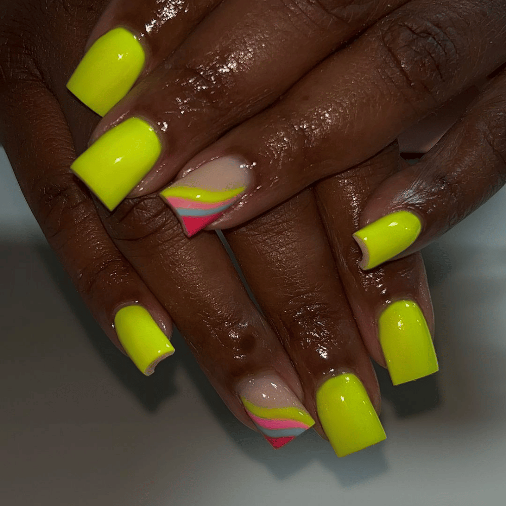 A close-up of a woman's hands showcasing vibrant neon yellow and pink nails, highlighting a bold and colorful manicure.