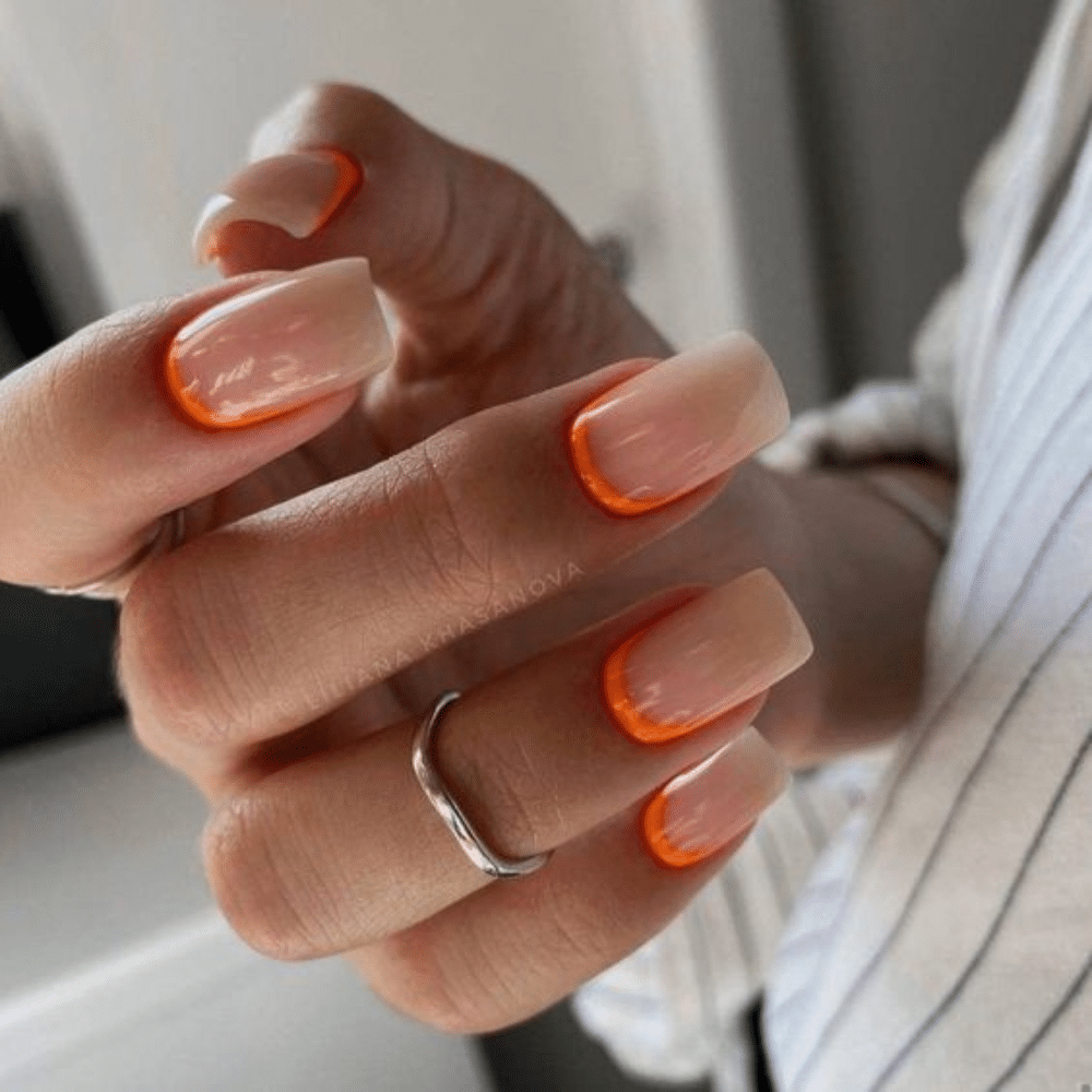 Close up of nails with glittery orange nails having Reverse Orange French Tips