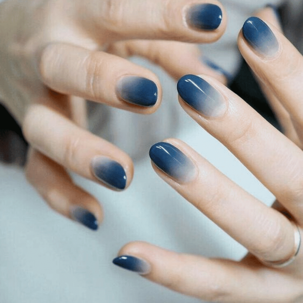 A woman showcasing her blue ombre hairstyle and matching blue nails, exuding a stylish and vibrant look.