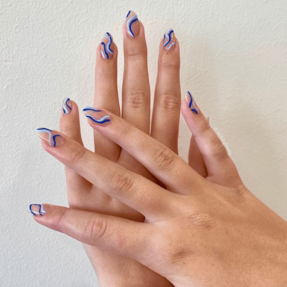 A close-up of a woman's hands adorned with intricate blue and white designs, showcasing artistic nail art.