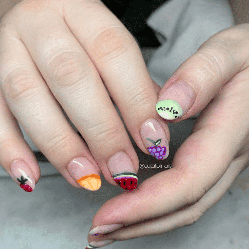 A person showcases their manicured nails adorned with colorful fruit designs, highlighting creativity and style.