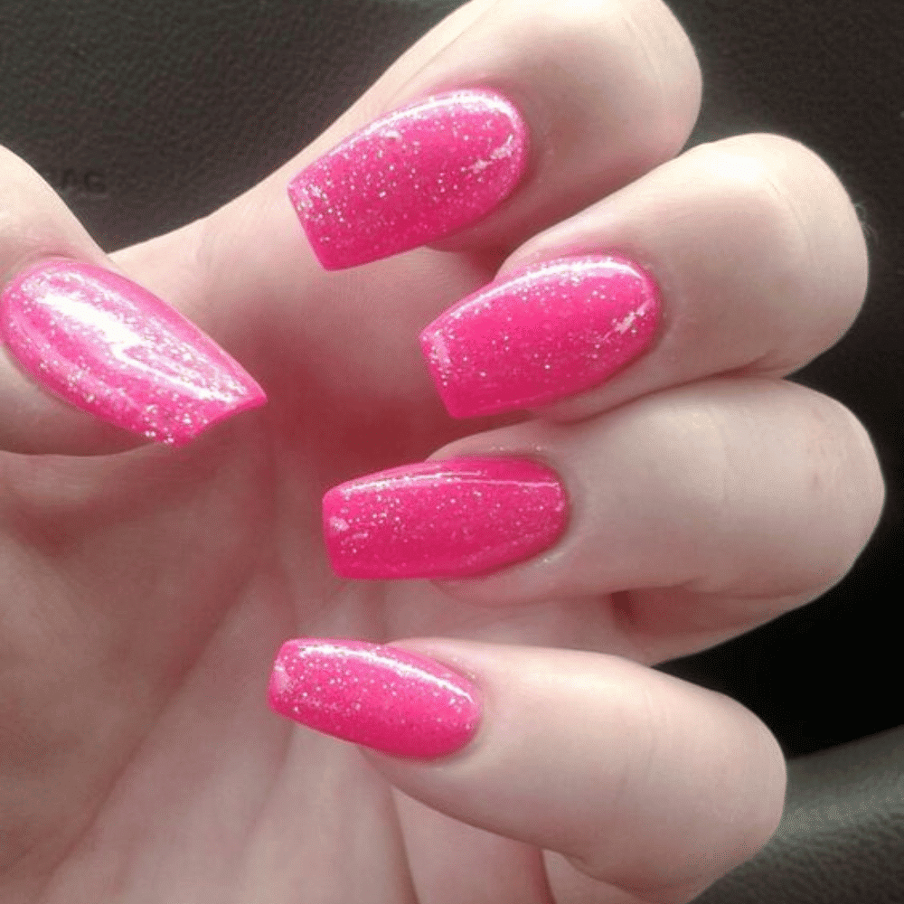 Hand with long, bright pink nails adorned with glitter