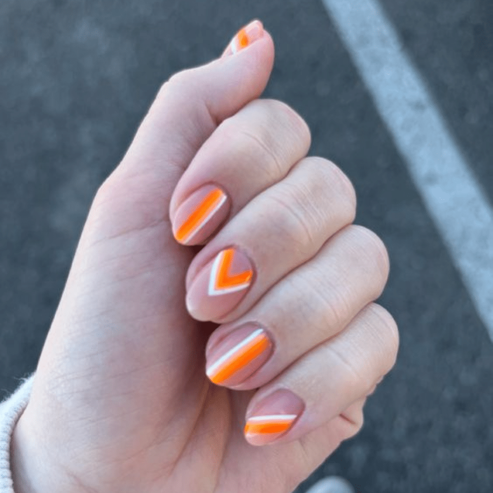 Close up of nails with glittery orange nails having Orange Geometric Patterns