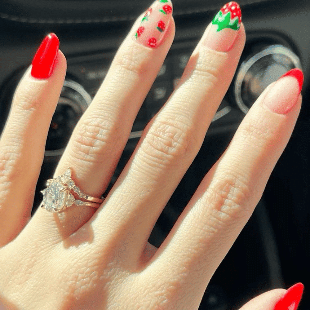 A woman displays a ring while showcasing her red and pink manicured nails.