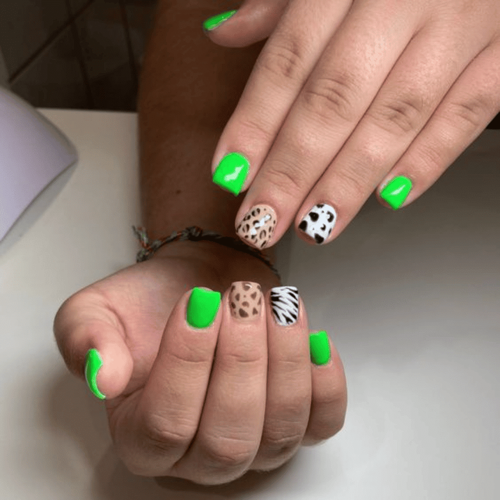 A woman showcasing her green nails complemented by a stylish leopard print manicure.