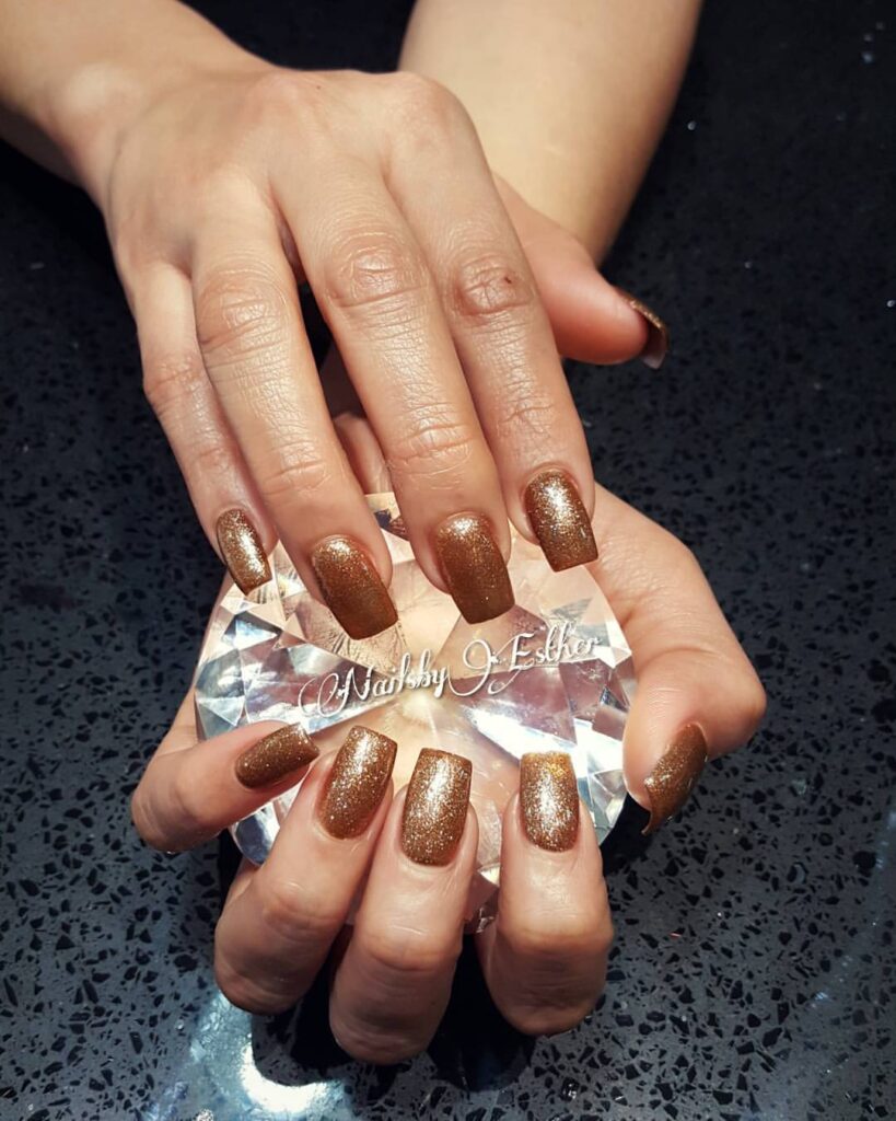 Close-up of hands with fall nail design having Bronze Shimmer Effects