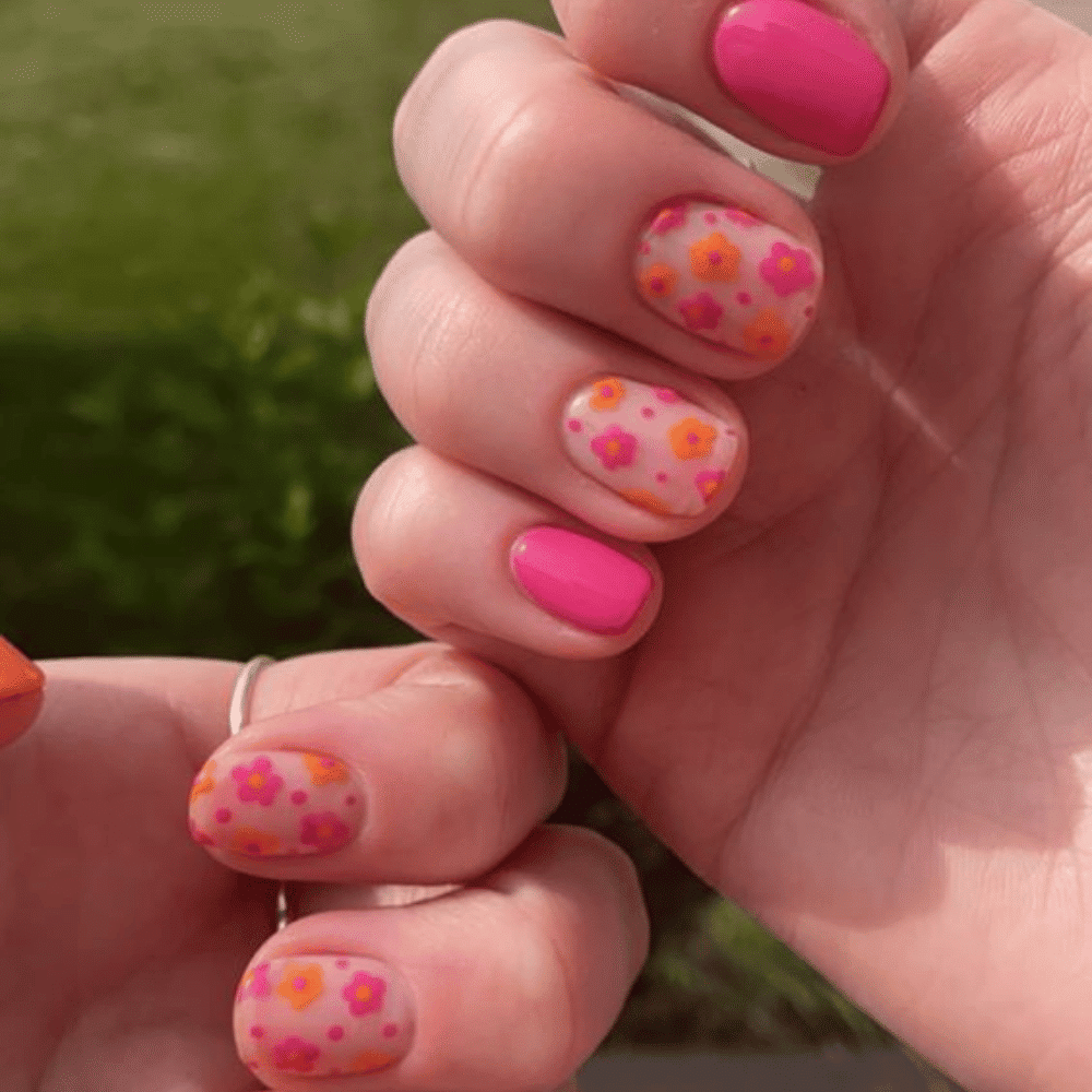 Two hands displaying vibrant pink and orange nail designs, showcasing a stylish and colorful manicure.