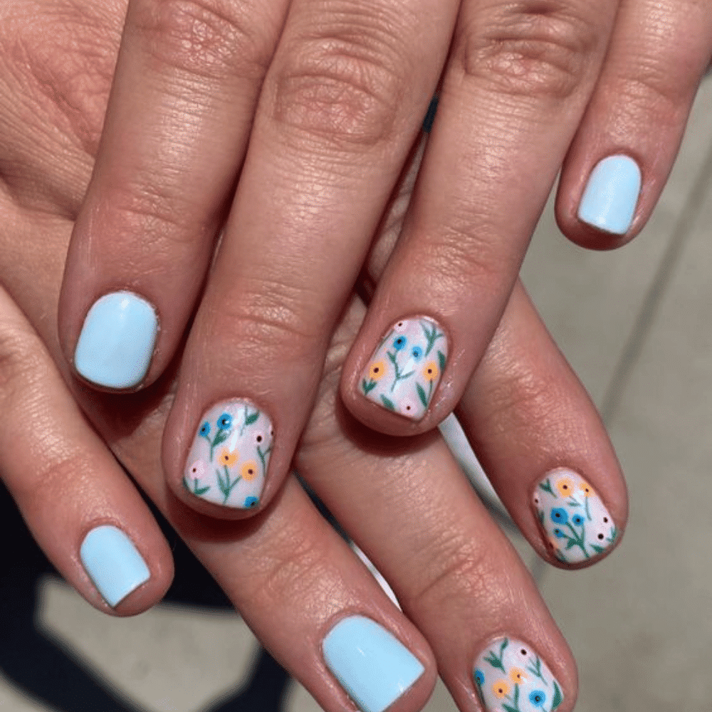 A close-up of a woman's hands adorned with delicate blue and white flowers, showcasing a unique floral design.