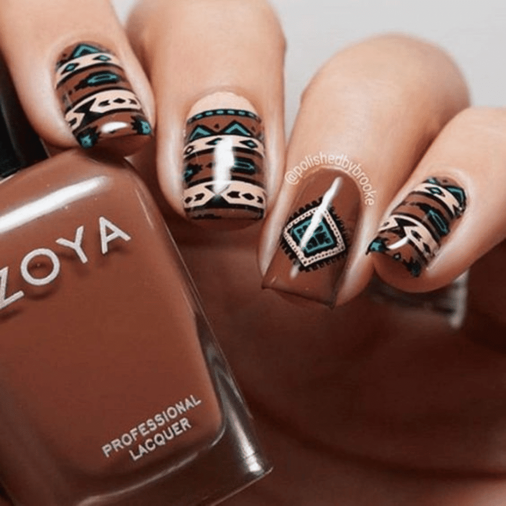 A woman displays a bottle of nail polish featuring a striking brown and blue tribal design.