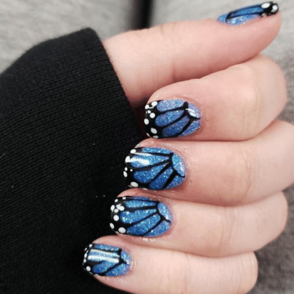 Elegant blue butterfly nail art design featuring intricate patterns and vibrant colors on manicured nails.