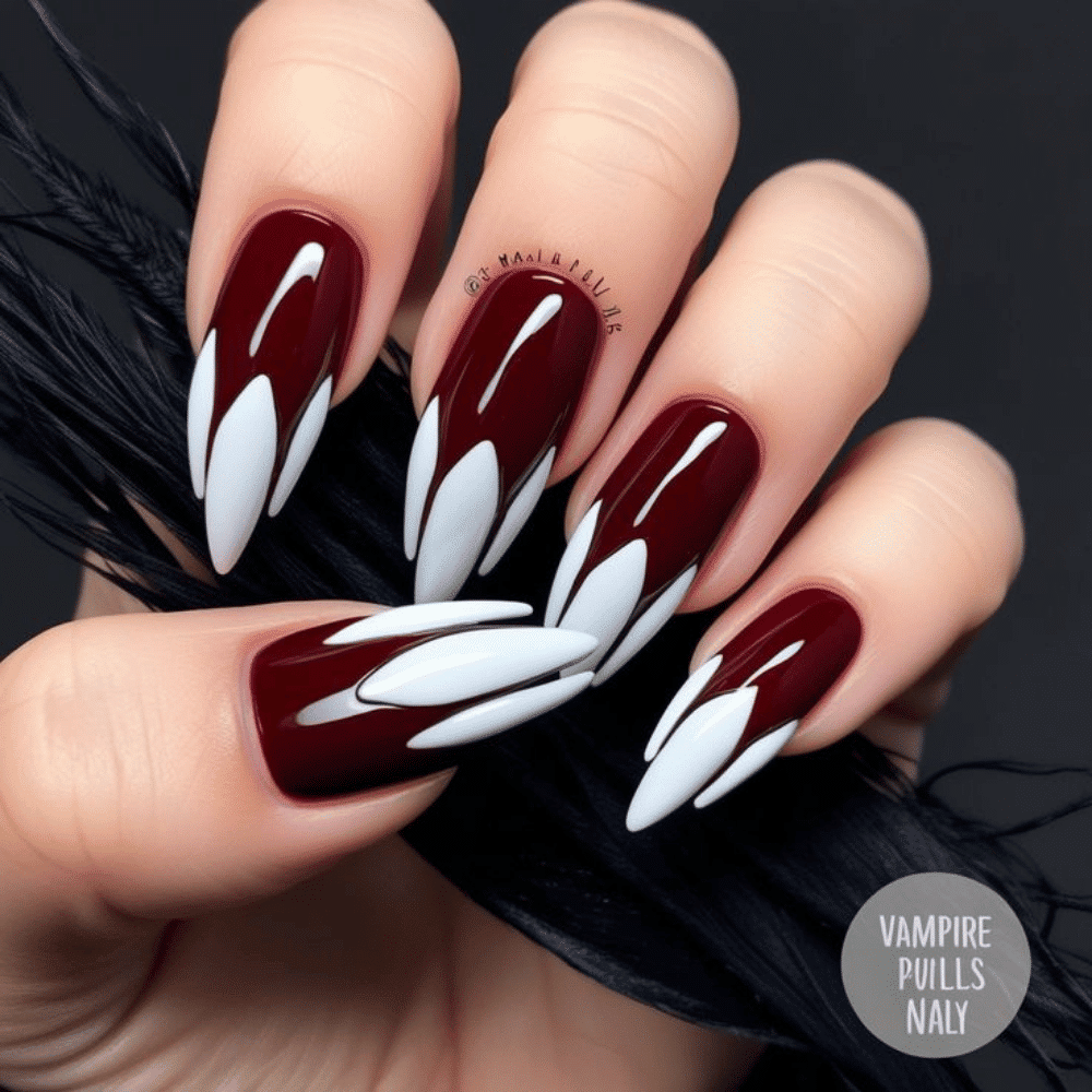 Hand with long, almond-shaped nails painted deep burgundy with white fang designs, and a black feather background.