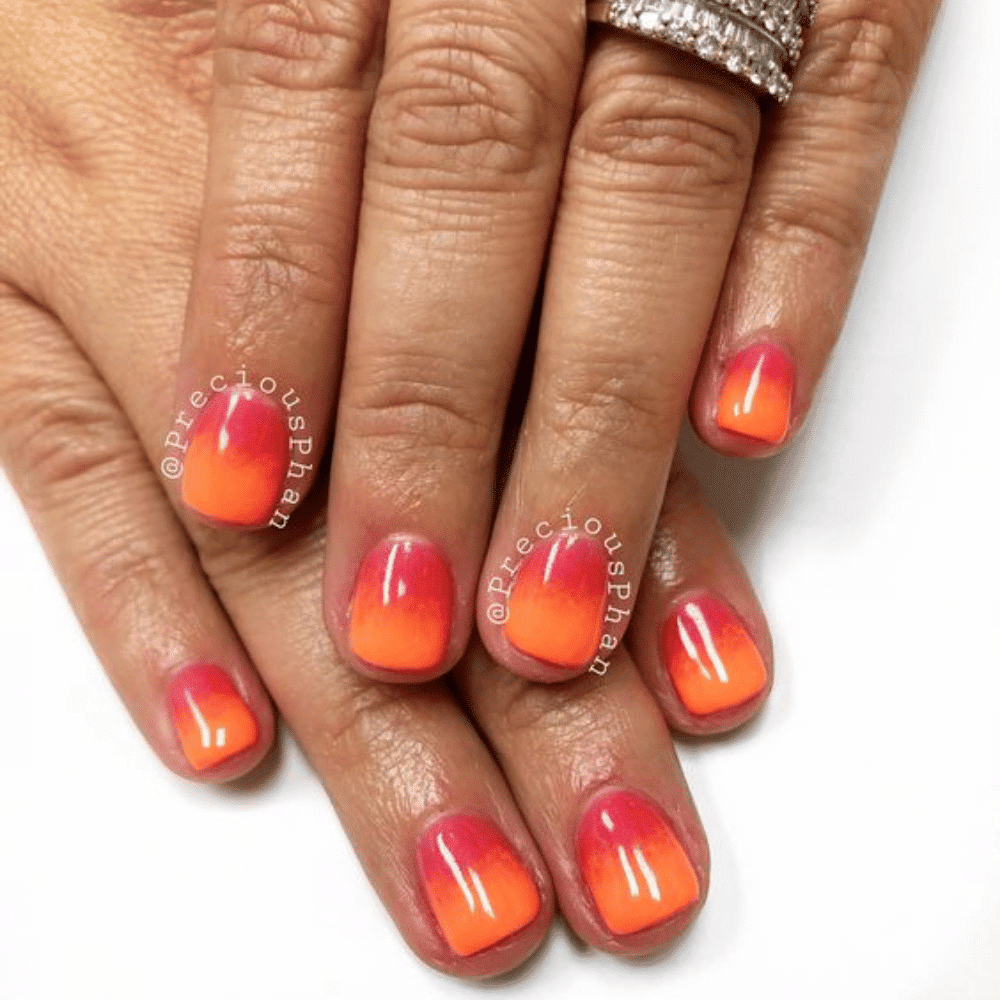 A close-up of orange and red ombre nail art, showcasing a smooth gradient effect from vibrant orange to deep red.