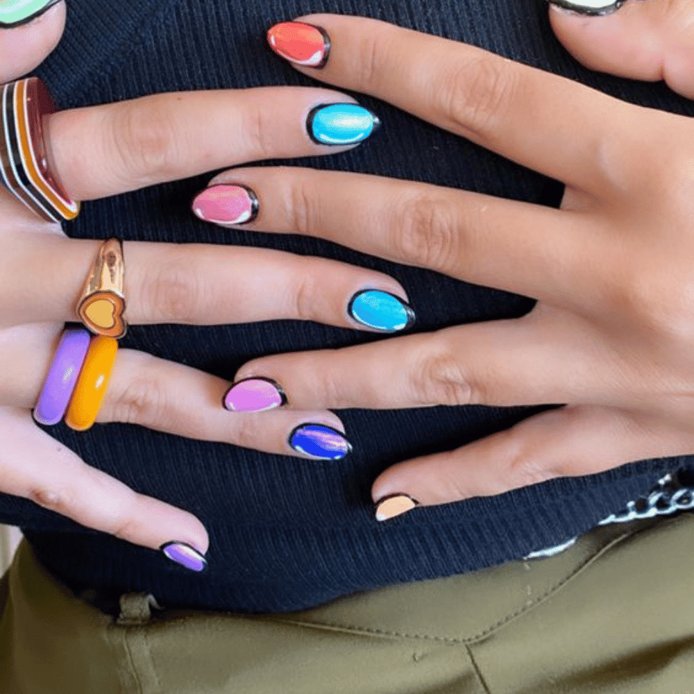 A woman showcasing her hands adorned with vibrant and artistic nail designs, highlighting creativity and style.