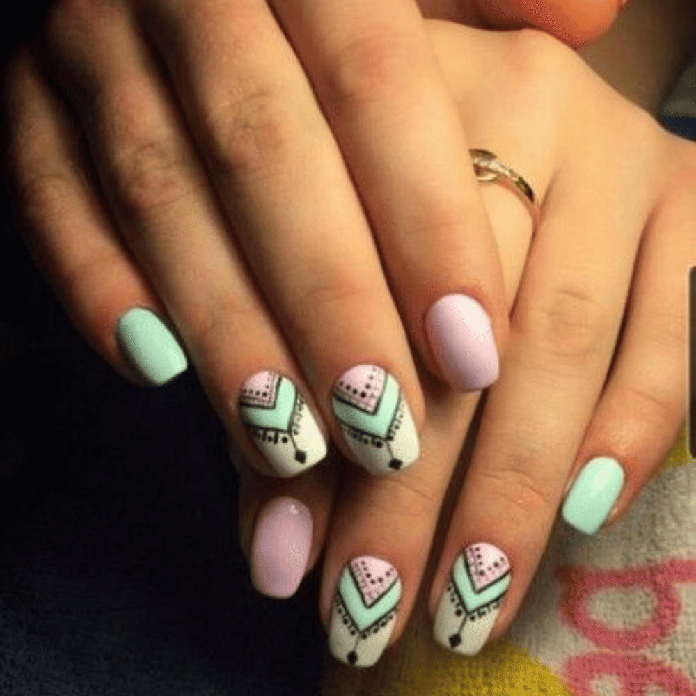 A close-up of a woman's hand showcasing a manicured nail featuring an intricate tribal design.