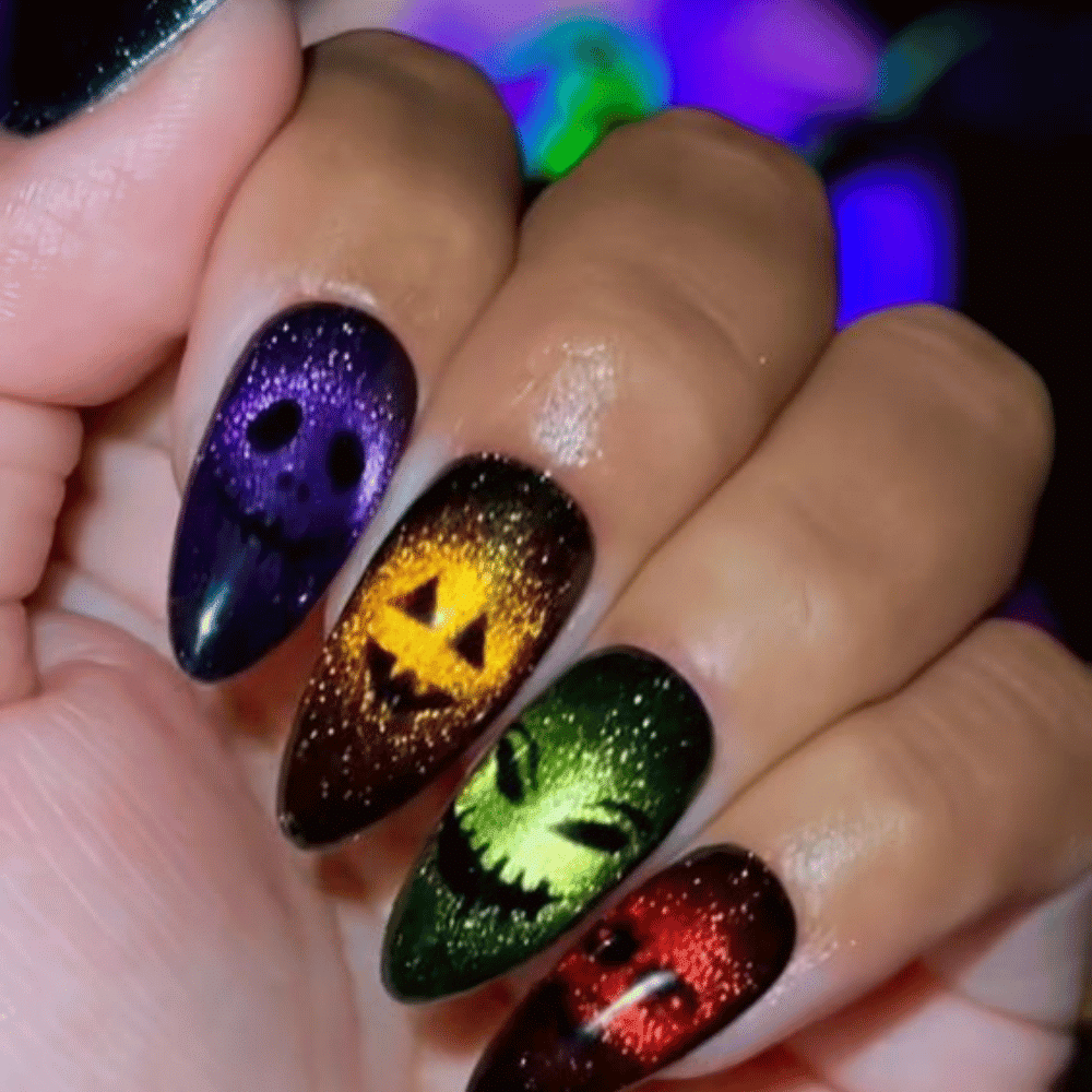 The image shows a hand with long, almond-shaped nails featuring Halloween-themed designs like skulls and jack-o'-lanterns.