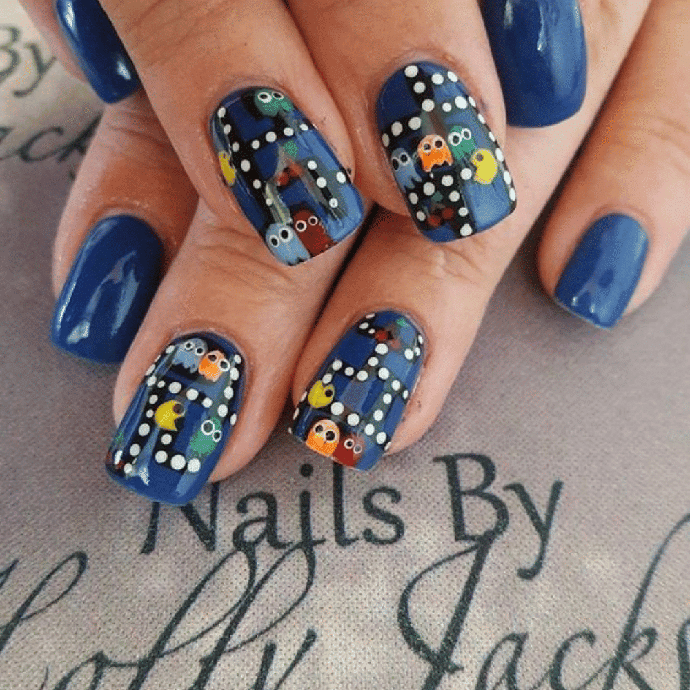 A close-up of a woman's hand showcasing blue nails adorned with vibrant, colorful designs.