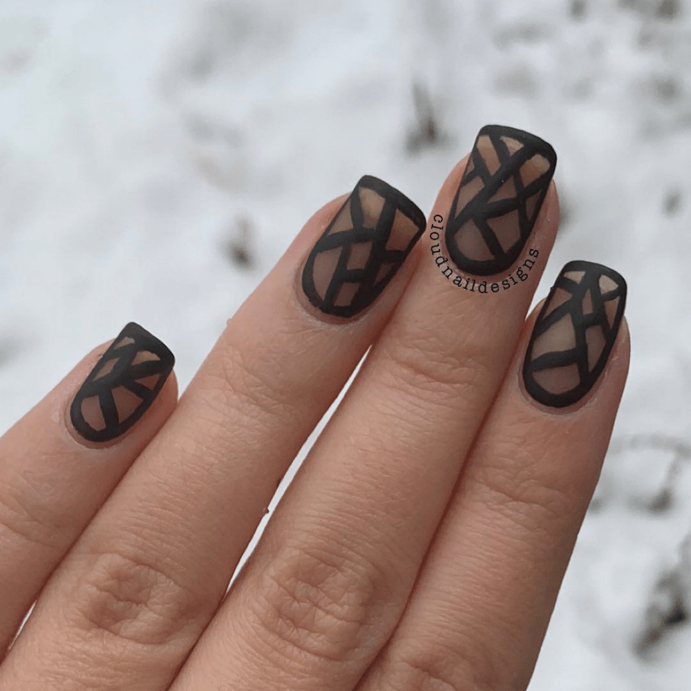 A close-up of a woman's hand showcasing stylish black and white nail art.