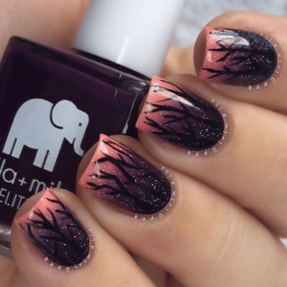 Hand with long, intricate purple gradient nails featuring black branch-like patterns and glitter, holding nail polish.