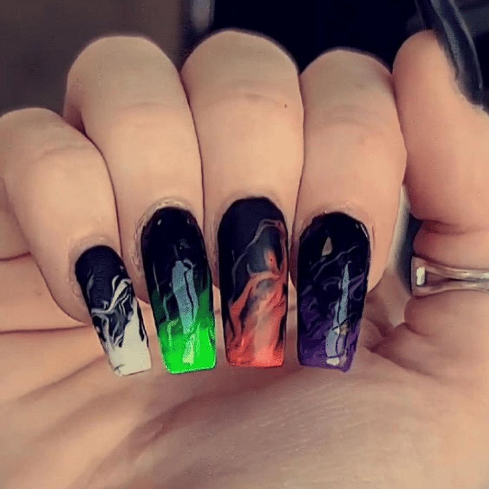 Hand with long, square-shaped nails featuring black bases and colorful gradient tips in white, green, orange, red, and purple