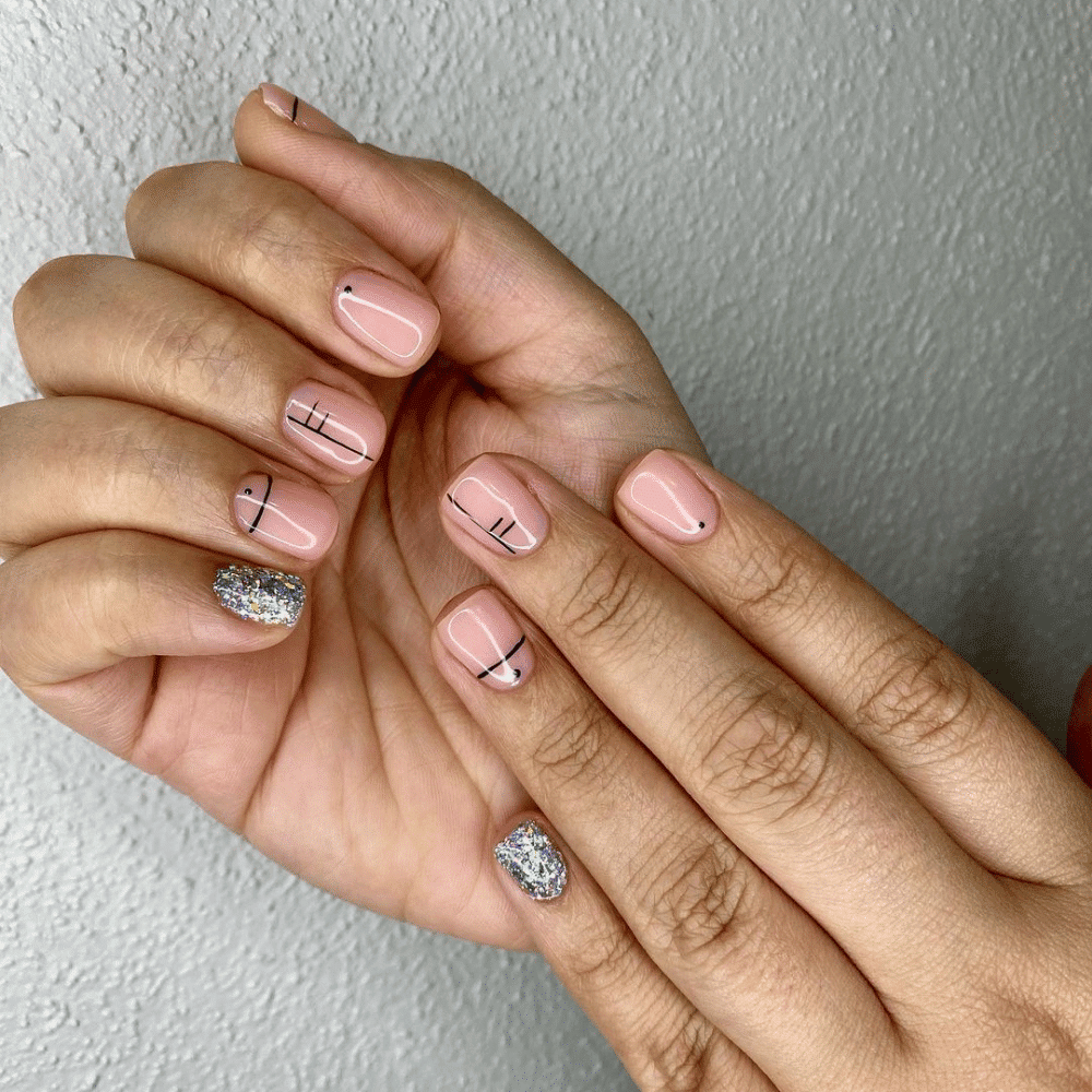 A close-up of a woman's hand showcasing elegant pink and silver nail designs, highlighting intricate artistry and style.