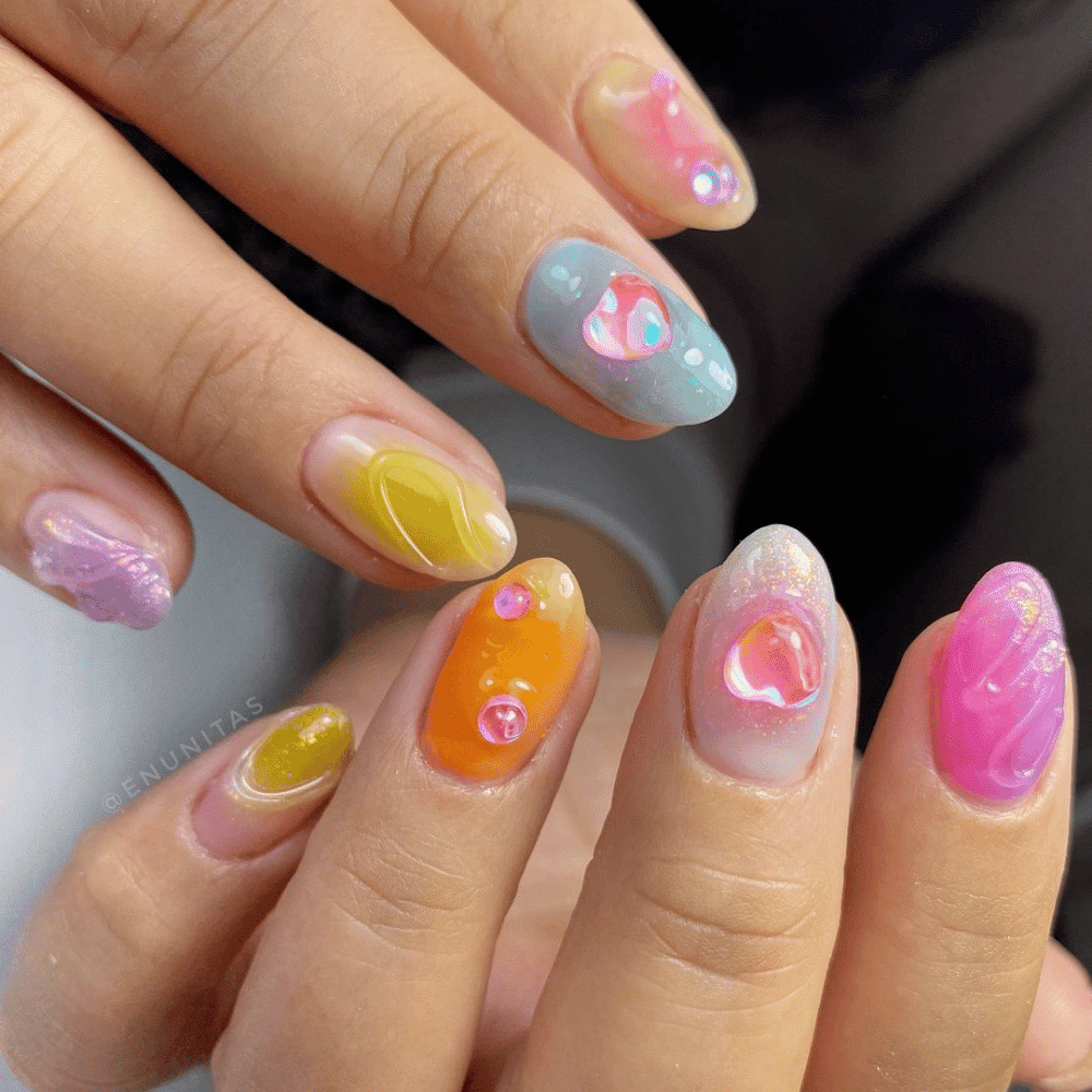 A woman showcasing her vibrant and artistic nail designs on her fingers, highlighting creativity and style.