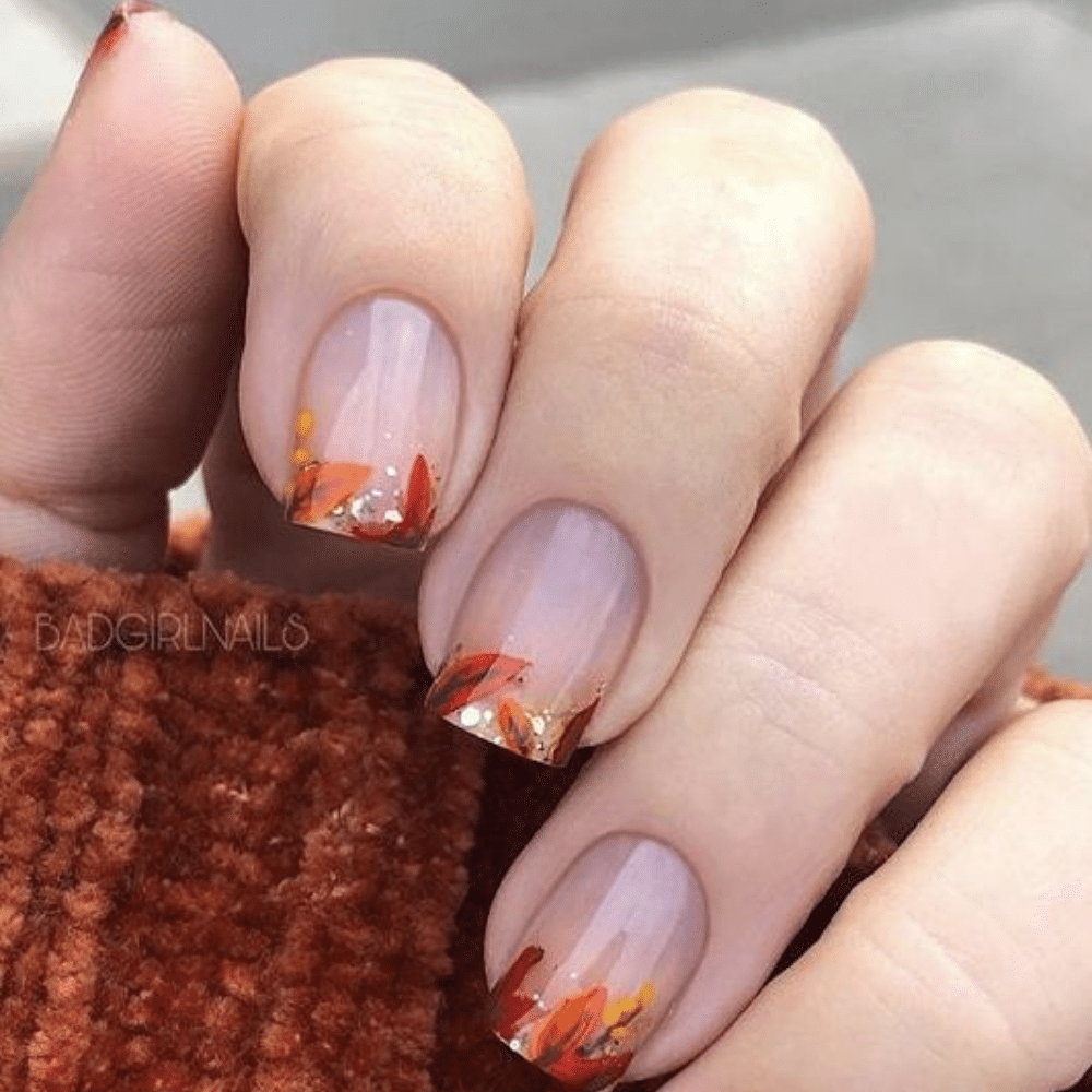 Close-up of a hand with white French tip autumn leaves nail