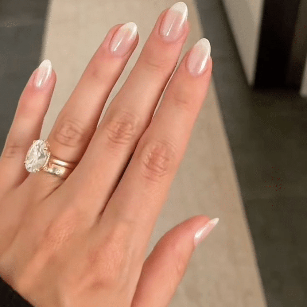 Close-up of a hand with white French tip nail with pearlescent polish