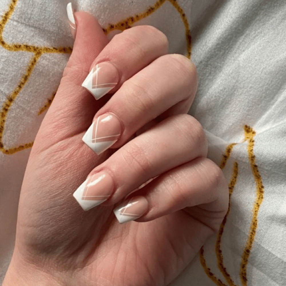 Close-up of a hand with white French tip nail having asymmetrical tips