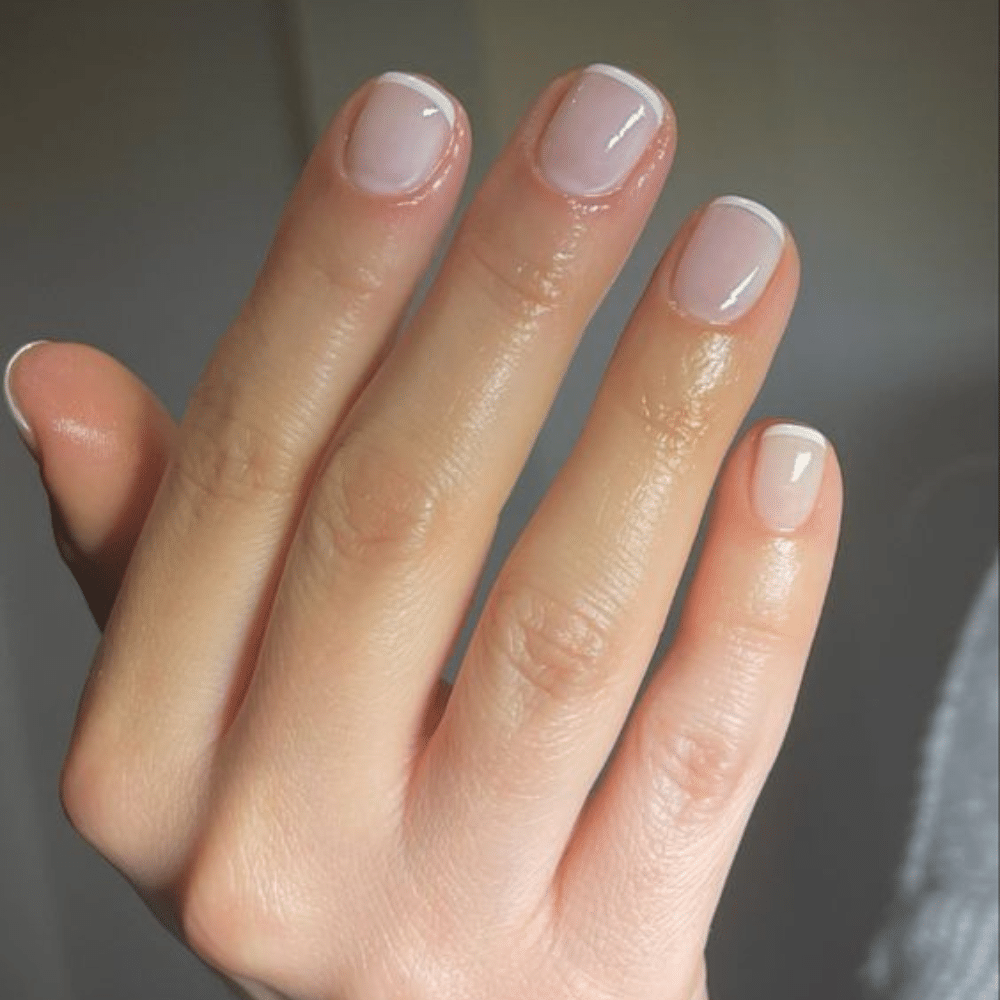 Close-up of a hand with white French tip nail with petite perfection