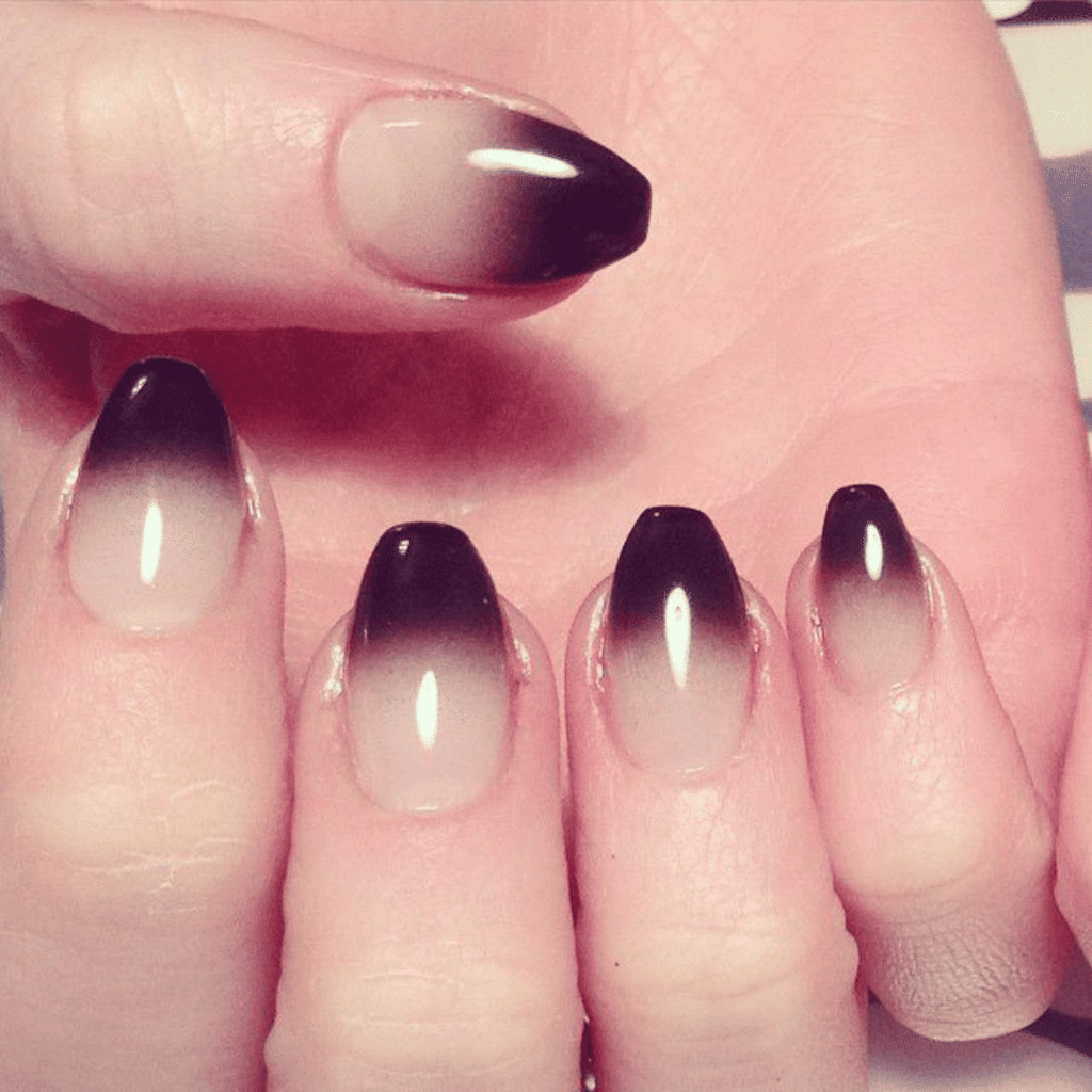 Five fingers with long, oval-shaped nails featuring a glossy ombre transition from clear to black.